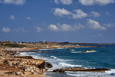 Kıbrıs Rum Kesimi 'nin Kıbrıs adasındaki plajda deniz feneri ve şemsiyeli Akdeniz kıyısının kayalık kıyıları