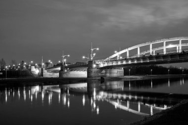 Polonya 'nın Poznan şehrinde gece boyunca Warta Nehri üzerindeki yol köprüsünün çelik yapısı tek renkli.