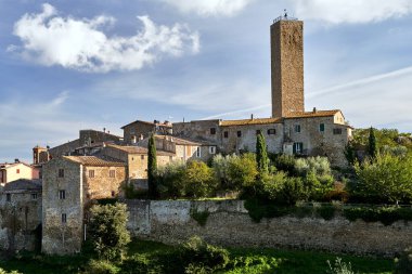 İtalya 'nın Toskana kentindeki Pereta kasabasının tepesinde taş evler, çan kulesi ve ortaçağ kulesi.