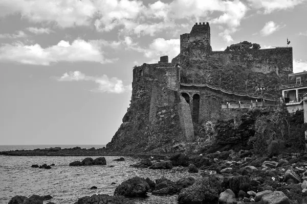 stock image Ruins of a Norman castle on a volcanic cliff in the village of Aci Castello on the island of Sicily, Italy,  monochrome