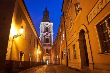 Geceleyin Poznan, Polonya 'da bir barok kilisesinin kaldırımlı sokak ve çan kulesi.