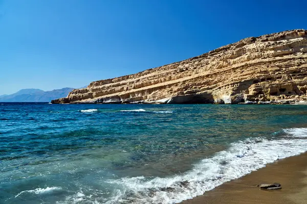 Yunanistan 'ın Girit adasındaki kumlu Matala plajının üzerindeki kayalık kayalar