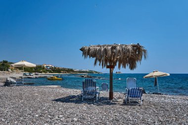 Yunanistan 'ın Rodos adasının kıyılarına demirlemiş deniz yatakları ve motorlu tekneleri olan kayalık bir sahil.