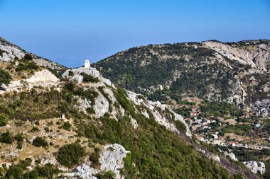 Yunanistan 'ın Lefkada adasındaki dağ yamaçlarının arasında bir kayanın üzerindeki Ortodoks şapelinin çan kulesi.