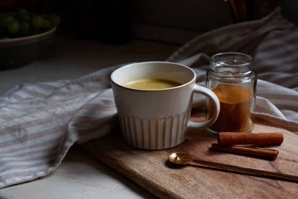 stock image golden latte, cup of hot turmeric latte with cinnamon sticks on wooden cutting board