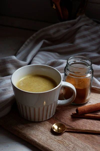 Złote Latte Filiżanka Gorącej Latte Paluszkami Cynamonowymi Drewnianej Desce Krojenia — Zdjęcie stockowe