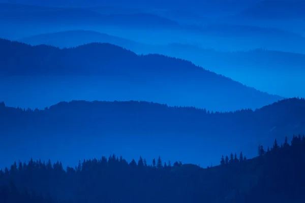 Blue misty mountain silhouettes in the morning. Artistic photo of Carpathian mountain ranges