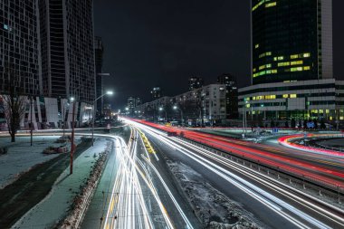 Kış şehrinde gece trafiği. Otobanda bulanık araba farı izleri var.