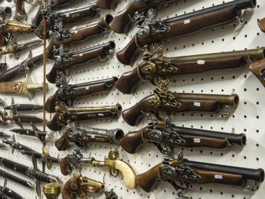 Set of old souvenir pistols and other Medieval weapon on the souvenir shop shelves in Gybbio, Italy