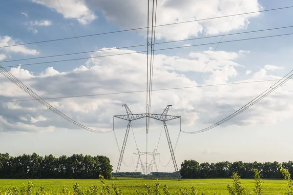 Electric wires and power line pylons on the green countryside field. Electricity grid and power distribution