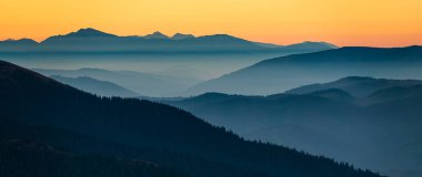 Mountain sunset header. Foggy valleys and blue mountain contours panorama