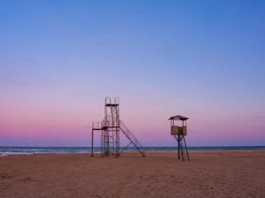 Empty sand beach at the sunset. Rescue tower and beach attractions at the seaside