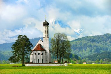 Arka planda yüksek dağ zirveleri olan yeşil alp çayırındaki resim gibi kilise. Almanya ve Avrupa 'da Bavyera manzarası
