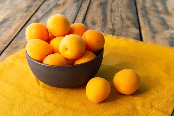 在饭桌上的餐巾上的碗里放着成熟的黄色杏仁 — 图库照片