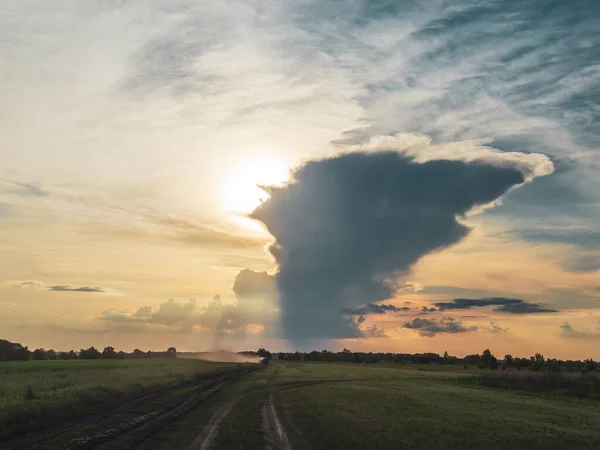 Growing thunderstorm cloud and countryside dirt road