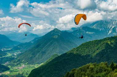 08.12.2022 Tolmin, Slovenya. Slovenya, Tolmin yakınlarındaki dağlarda renkli yamaç paraşütü kanatları uçuşuyor. Soca Vadisi, Avrupa 'nın popüler turizm merkezi, ekstrem sporlar ve aktif yaşam tarzı için Mekke.