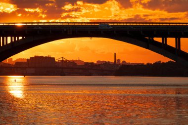 Kyiv şehrinin silueti. Kyiv Metro köprüsü ve Dnipro nehri gün batımında