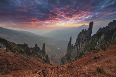 Dramatik dağ manzarası. Keskin iğne kayalar ve canlı günbatımı gökyüzü dağların tepesinde..