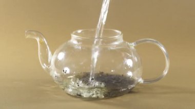 Sıcak su, cam çaydanlığa siyah çayla doluyor.