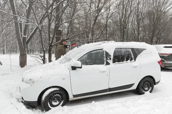 Car owner removing snow with a brush after a heavy snowfall