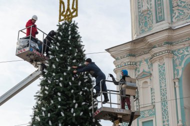 2023-12-05 Kyiv, Ukrayna. Erkekler Noel ağacını parlak çelenklerle süslemek için araba kuleleri kullanıyorlar.