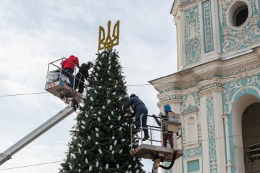 2023-12-05 Kyiv, Ukrayna. Erkekler Noel ağacını çelenklerle süslüyor araba kuleleri kullanarak.