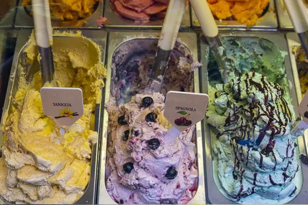 Variety of tasty Italian ice cream or gelato in steel bowls in gelateria shop, world famous tasty italian dessert