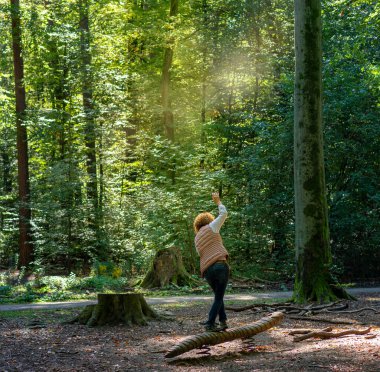 woman balancing on a tree trunk during a walk in the Berlin forest