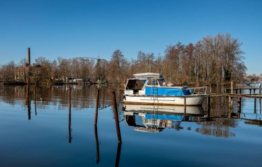 old motorboat, stands on a broken wooden pier on the Havel river in Spandau, Berlin, Germany