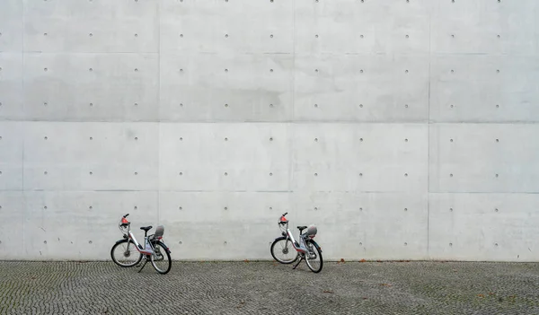 Dwa Wypożyczalnie Rowerów Stoją Przed Gołą Betonową Ścianą Berlin Dzielnica — Zdjęcie stockowe