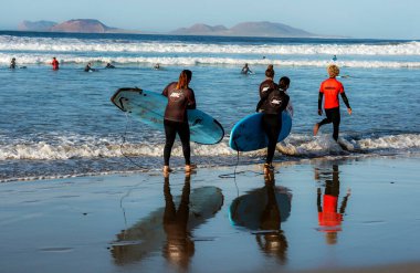 Plajda sörfçüler, Playa Famara, Lanzarote, Kanarya Adaları, İspanya, 2022, Kasım