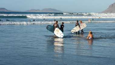 Plajda sörfçüler, Playa Famara, Lanzarote, Kanarya Adaları, İspanya, 2022, Kasım