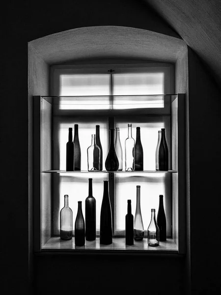 Ασπρόμαυρη Φωτογραφία Διακόσμηση Άδειων Φιαλών Κρασιού Μπροστά Από Ένα Φωτεινό — Φωτογραφία Αρχείου