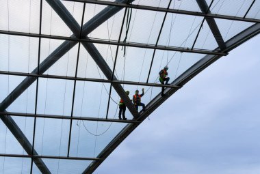 Craftsmen and fitters on the glass roof of the Elbbrcken train station, Hamburg, Germany clipart