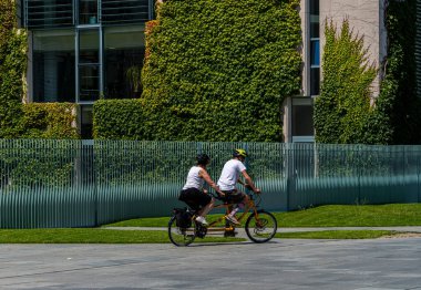 Tourists on bicycles, fence, at the Federal Chancellery, Berlin, Germany clipart