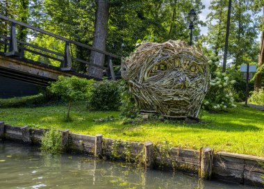 The image depicts a tranquil river landscape, with boats, wooden bridges, and single-family homes along the water. Surrounded by nature and landscape, the scene has a natural and peaceful atmosphere. Lbbenau, Brandenburg, Germany