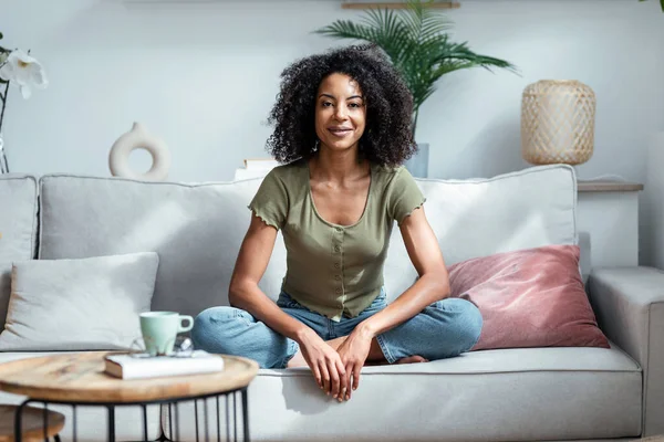 stock image Shot of beautiful woman looking at camera while sitting on couch in living room at home.