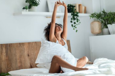 Genç ve güzel kadın uyku modundan çıkarma sonra yatak odasında germe kadeh.