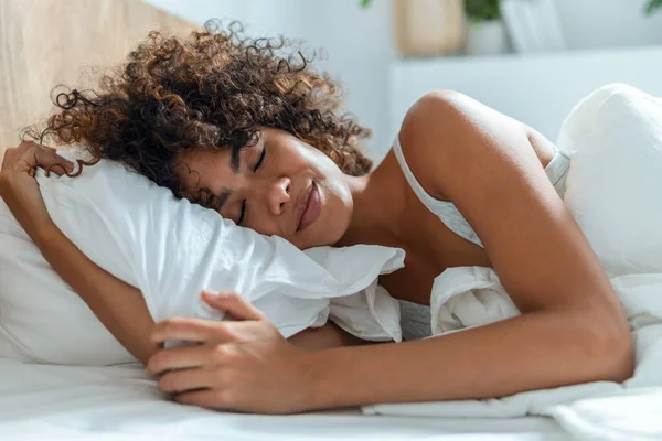 Shot of kind woman sleeping peacefully while hugging the pillow on the bed.