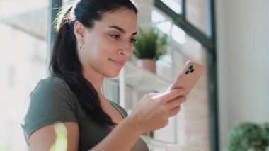 Evdeki mutfakta bir fincan kahve içerken cep telefonunu kullanan genç ve güzel bir kadının videosu..
