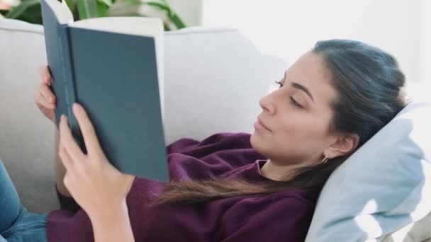 Video Wanita Muda Cantik Membaca Buku Sambil Duduk Sofa Rumah — Stok Video