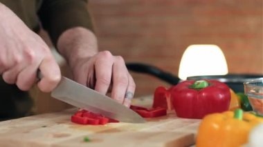 Yakışıklı, olgun bir adamın evde mutfaktaki kulaklıkla müzik dinlerken taze sebze kestiği yakın çekim videosu..