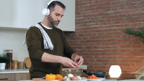Video Handsome Mature Man Preparing Omelette While Listening Music Dancing — Stock Video