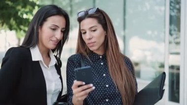 Şehirde kahve içerken akıllı telefon kullanan iki güzel iş kadınının videosu..