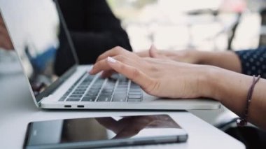 Bir bar terasında dizüstü bilgisayarıyla çalışan iş kadınlarının yakın çekim videosu.