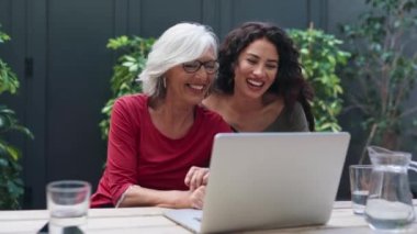 Moda büyükannesi ve güzel torununun bahçede bir bankta dizüstü bilgisayar kullanırken konuştuğu bir video..