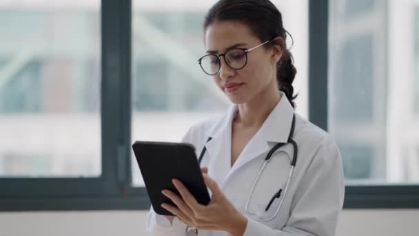 女医生站在诊疗所时使用数码平板电脑的录像 — 图库视频影像