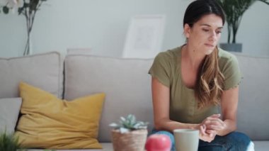 Evdeki oturma odasındaki kanepede oturmuş sorunları düşünen endişeli bir kadının videosu..