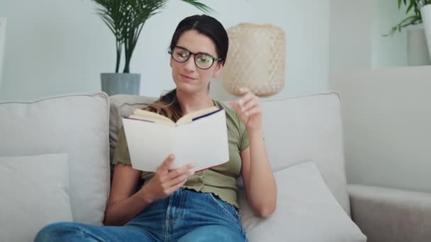 Wideo Pewnej Siebie Kobiety Czytającej Książkę Siedząc Kanapie Domu — Wideo stockowe