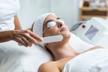 Güzellik uzmanının güzellik salonunda lazer tedavisinden önce güzel kadın yüzüne hidrojel maske takması..